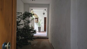 A hallway with a wooden door, a potted plant, and a hanging light fixture.