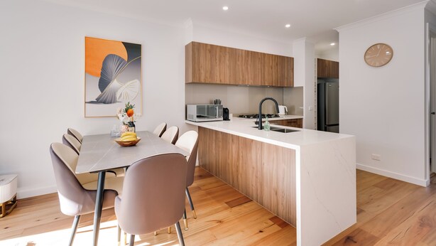 A modern kitchen with a central island, wooden cabinets, and a microwave. - StayAU Stylish 4BR Home Ringwood (Ringwood East)
