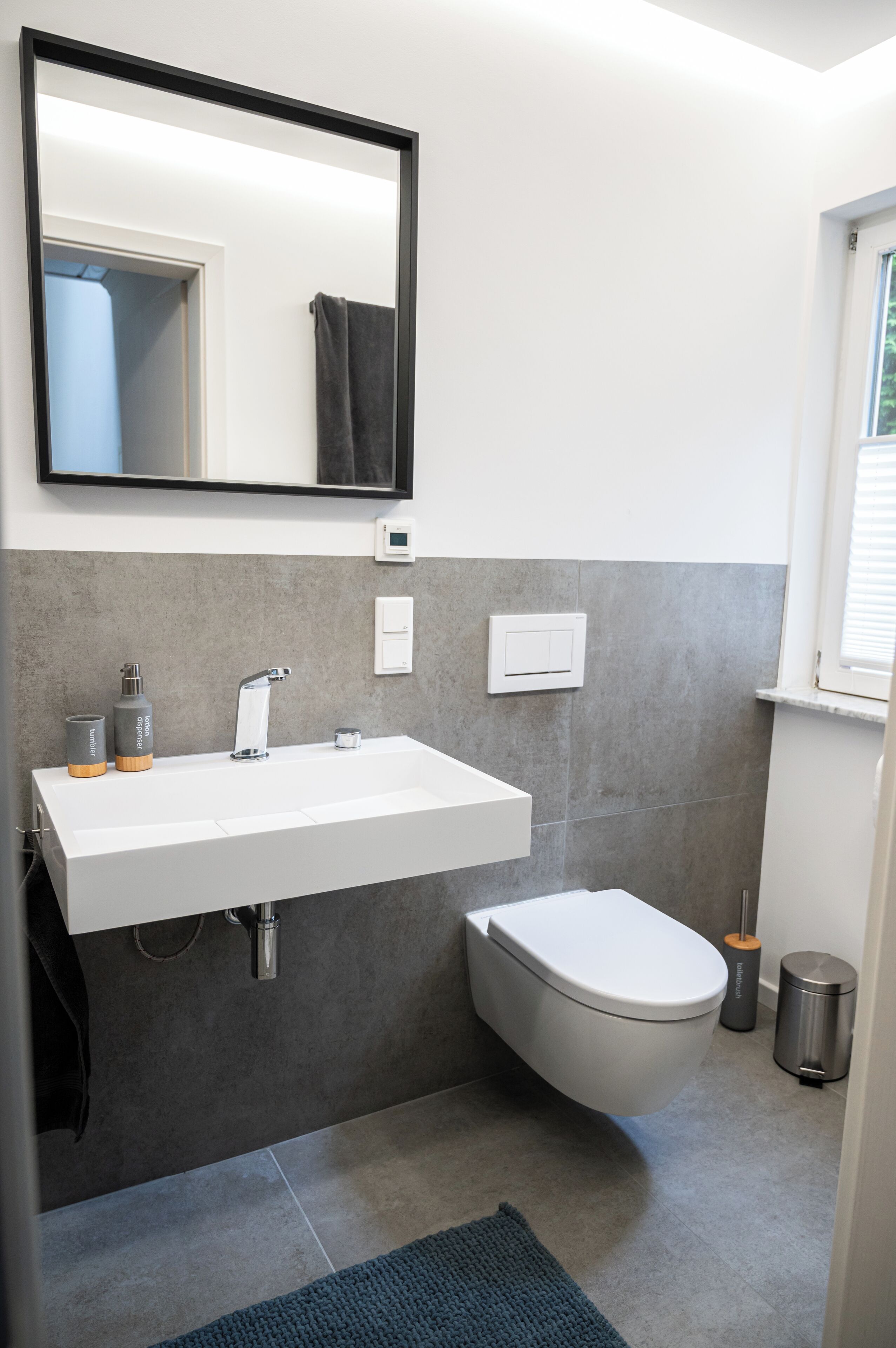 Un baño moderno con un lavamanos blanco, un inodoro y un espejo.