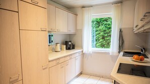 Une cuisine compacte avec des meubles de couleur bois clair, un four à micro-ondes, une machine à café et un évier.