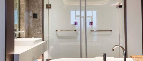 Un baño moderno con ducha de vidrio, bañera independiente y tocador con espejo.