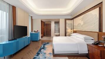 Une chambre d’hôtel moderne équipée d’un téléviseur à écran plat, d’un lit, d’un bureau et d’une grande œuvre d’art accrochée au mur.