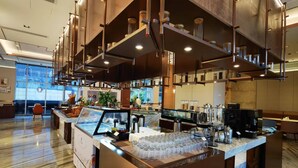 A modern bar area with a glass display case, coffee machines, and a seating area with a view of the outdoors. - Jiangshan Haiwaihai Hotel (Quzhou)