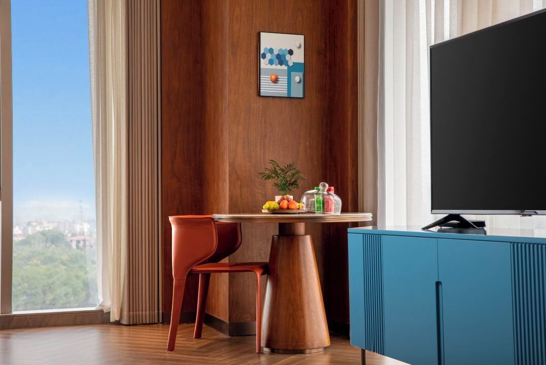 Ein modernes Zimmer mit einer Holzverkleidung, einem Esstisch mit Stühlen, einem Fernseher und Blick auf die Stadt.