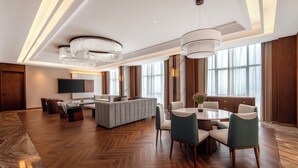 A spacious hotel lobby with a herringbone wood floor, a central seating area with a sofa and chairs, a dining table with chairs, and a large chandelier. - Jiangshan Haiwaihai Hotel (Quzhou)
