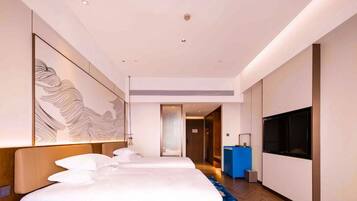 A hotel room with a large bed, a TV, a desk, and a decorative wall piece.