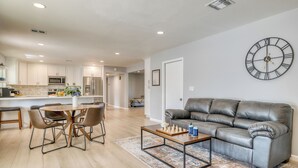 A modern living room with a leather sofa, a coffee table, and a dining area with chairs and a table. - Shalimar of Tempe by AvantStay | Pool, Patio, Grill | Near Golf + Entertainment (Tempe)