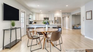A modern kitchen with white cabinets, a central island, and a dining area with a round table and chairs. - Shalimar of Tempe by AvantStay | Pool, Patio, Grill | Near Golf + Entertainment (Tempe)