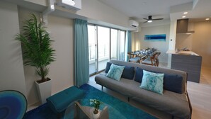 A modern living room with a sofa, a dining table, and a kitchen area. - Branchera Naha Akebono Premist 1206 (Naha)