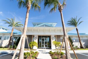 A hotel entrance with a clear pathway, palm trees, and a blue roof.