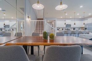 Eine moderne Küche mit weißen Schränken, einem Holztisch und einer Treppe zu einer oberen Ebene.