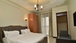 Une chambre d’hôtel avec un grand lit, une armoire, une chaise et un luminaire au plafond.