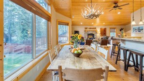 A spacious dining area with a wooden table, chairs, and a large window overlooking a backyard.
