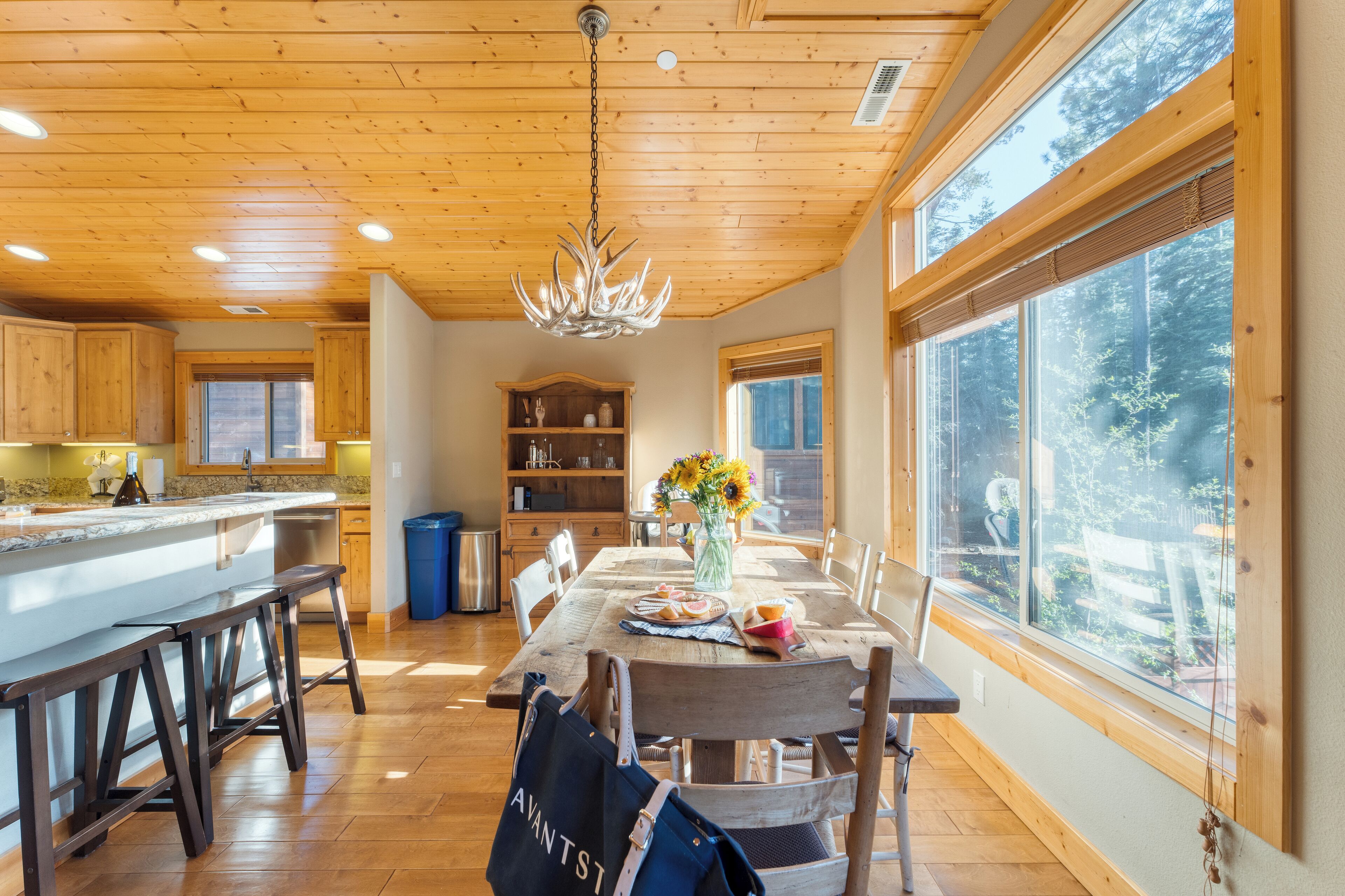 Une cuisine spacieuse dotée de meubles en bois, d’un grand îlot central et d’un coin repas avec une table dressée pour deux personnes.