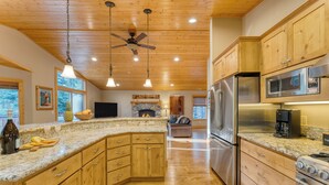 A spacious kitchen with wooden cabinets, granite countertops, stainless steel appliances, and a central island.