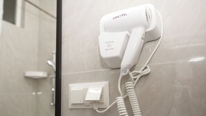 A hair dryer mounted on a wall with a power outlet below it. - ASYL HOTEL (Astana)