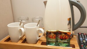 A wooden tray with two white mugs, a kettle, and two packets of Greenfield tea. - ASYL HOTEL (Astana)