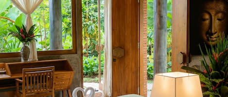 Una habitación con una cama, un escritorio, una silla, una lámpara y una estatua de Buda.