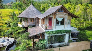 A two-story house with a balcony, surrounded by lush greenery and a rice field. - Villa OMantra Home Bali (Sukasada)