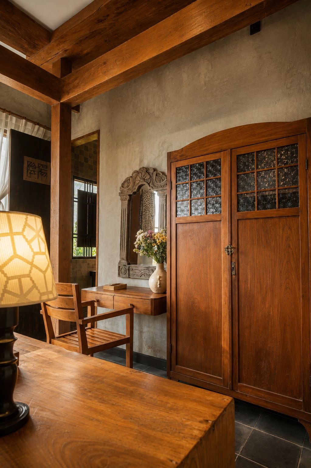 Una mesa de comedor de madera con sillas, un florero con flores y un aparador de madera con puertas de cristal.