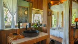 A wooden room with a large mirror, a basin, and a bed with a canopy. - Villa OMantra Home Bali (Sukasada)