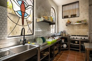 A kitchen with a stainless steel sink, a stove, and a window with a stained glass design. - Villa OMantra Home Bali (Sukasada)