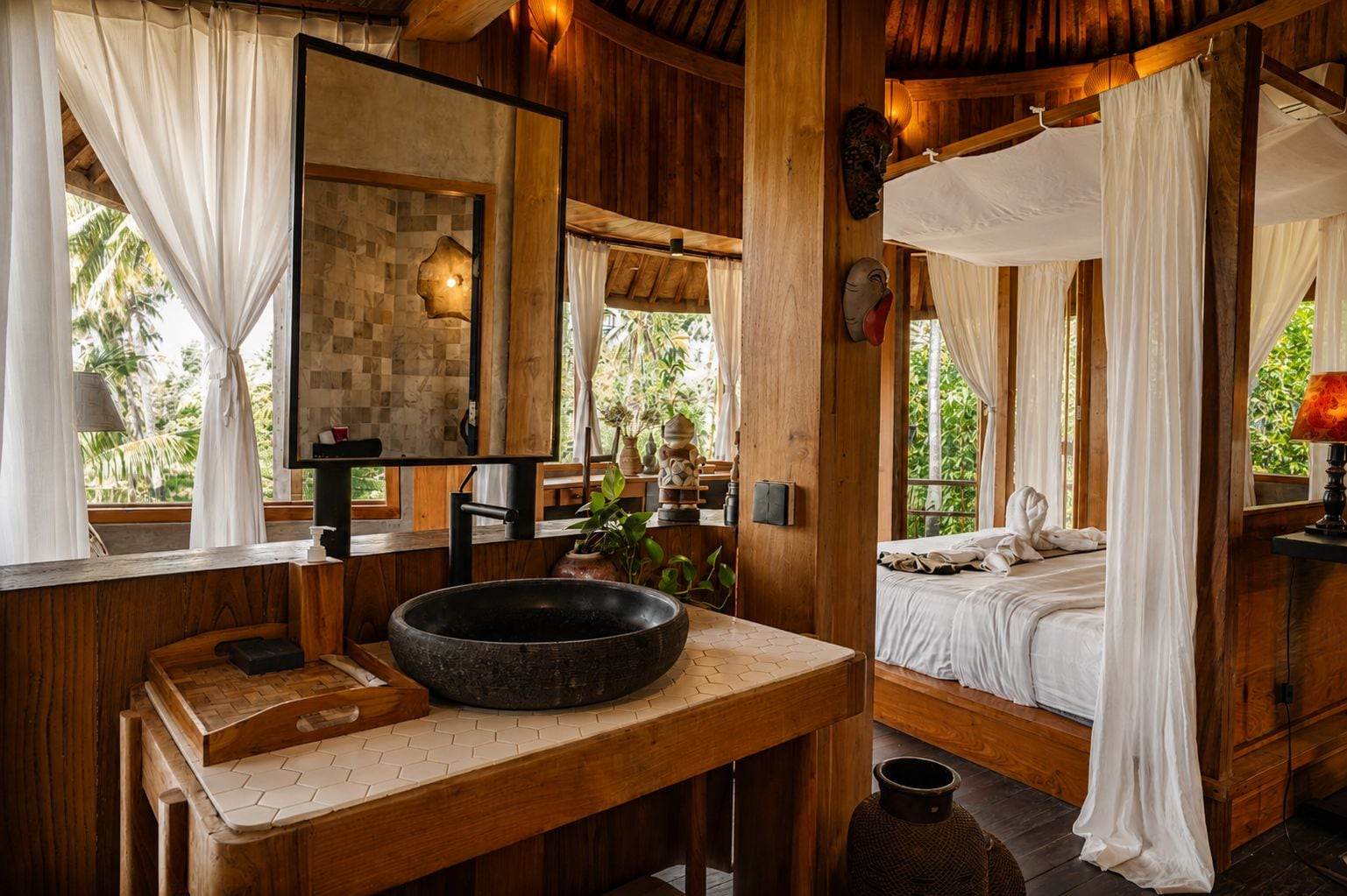 Una cabaña de madera con un espejo grande, un lavabo de piedra, una cama con dosel y vistas al verdor exterior.