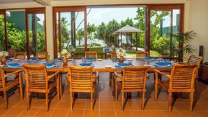 A dining area with a large table set for multiple people, surrounded by wooden chairs. - South Point Ocean - Whole Villa 8 Bedroom (Sleep 16) (Koggala)