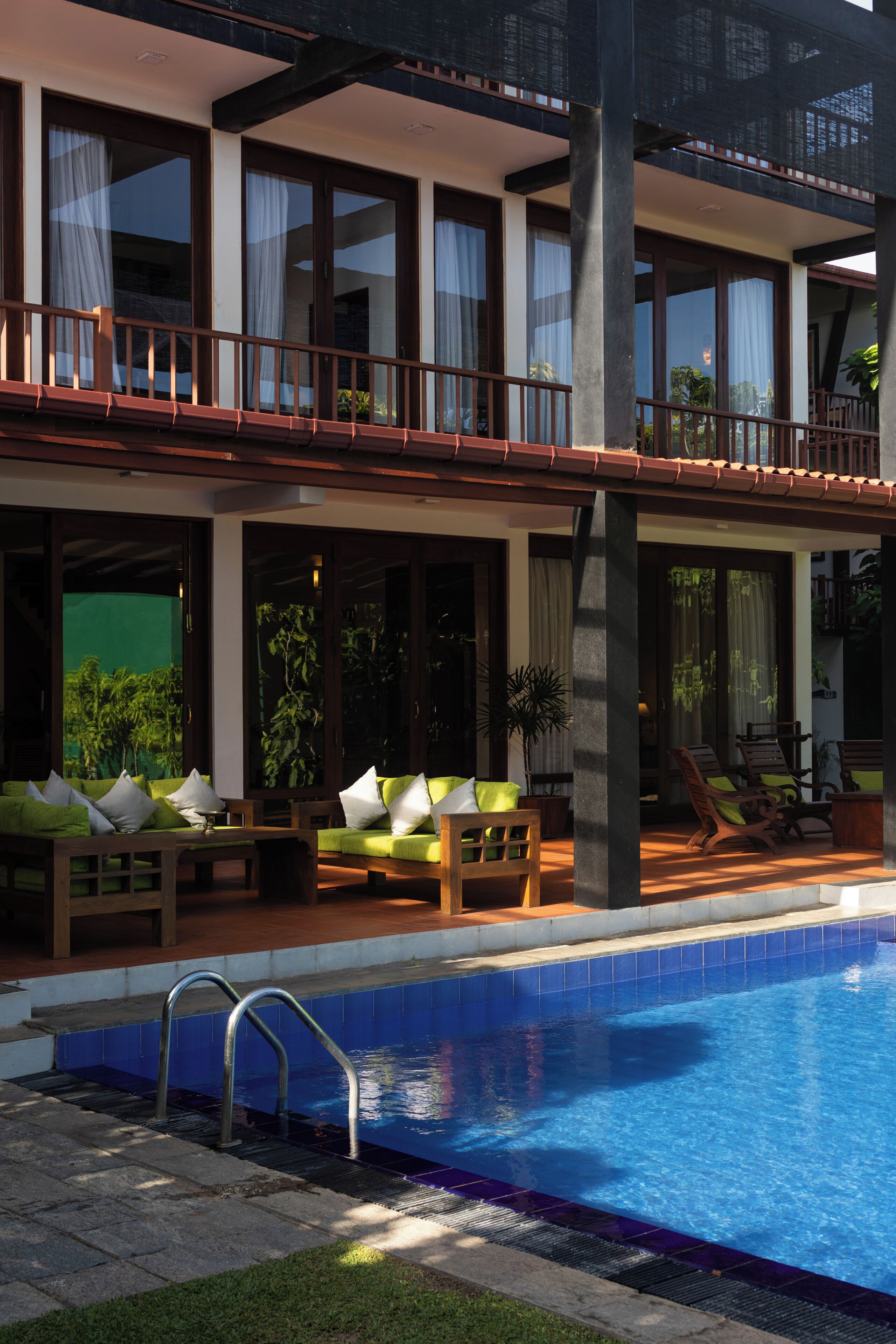 A two-story building with a swimming pool, outdoor seating, and large windows.