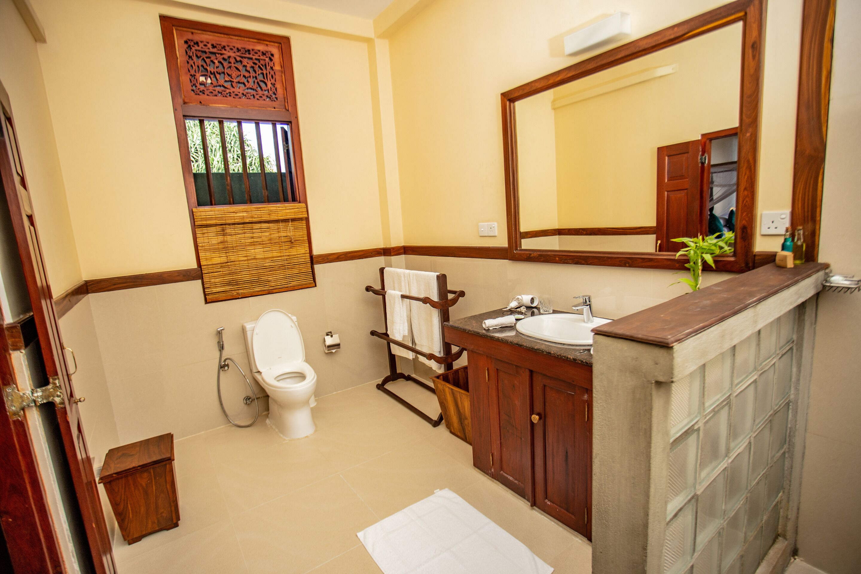 A bathroom with a toilet, sink, mirror, and wooden cabinet.