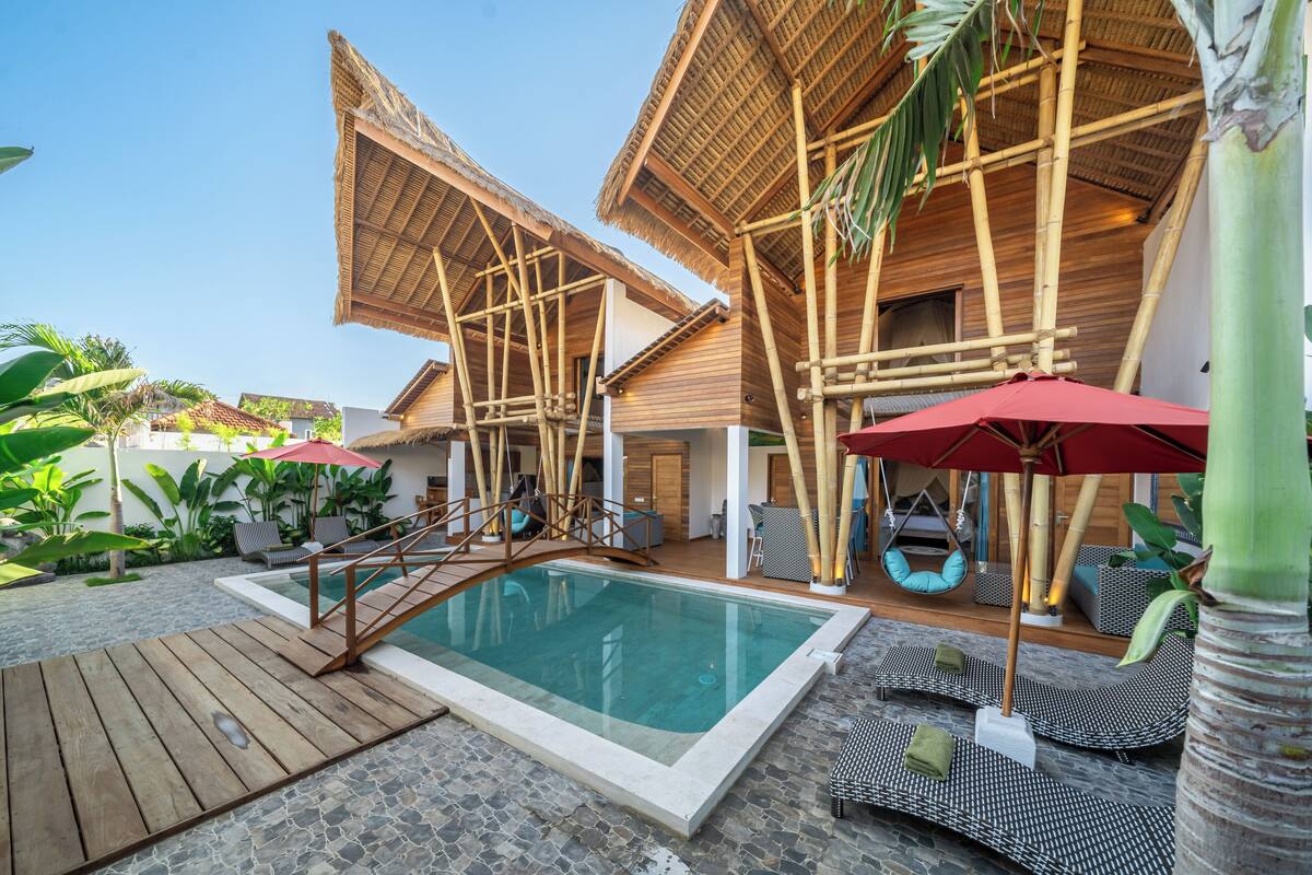 A pool area with wooden deck, lounge chairs, and umbrellas.