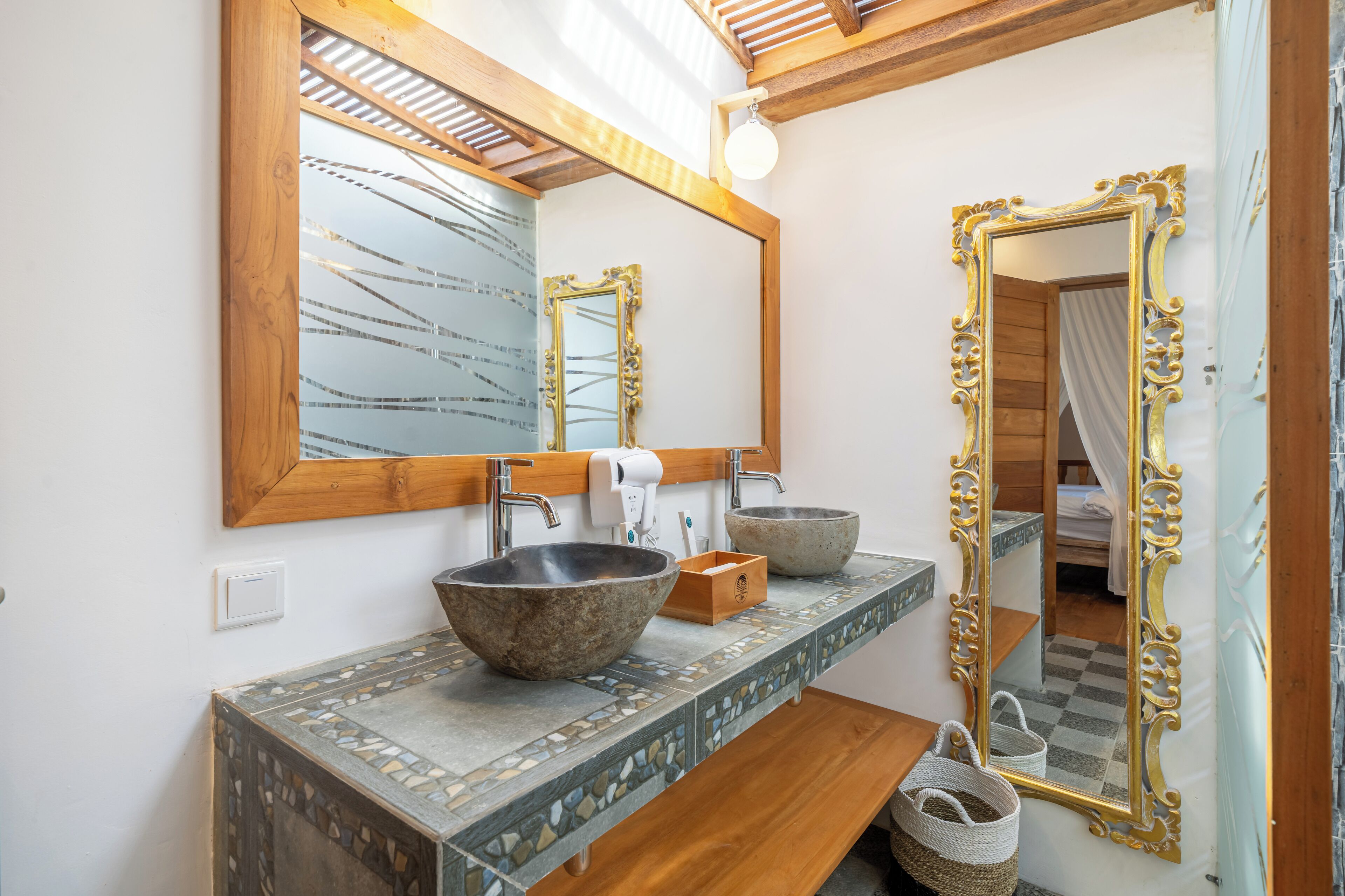 A bathroom with a large mirror, two sinks, and a wooden vanity.