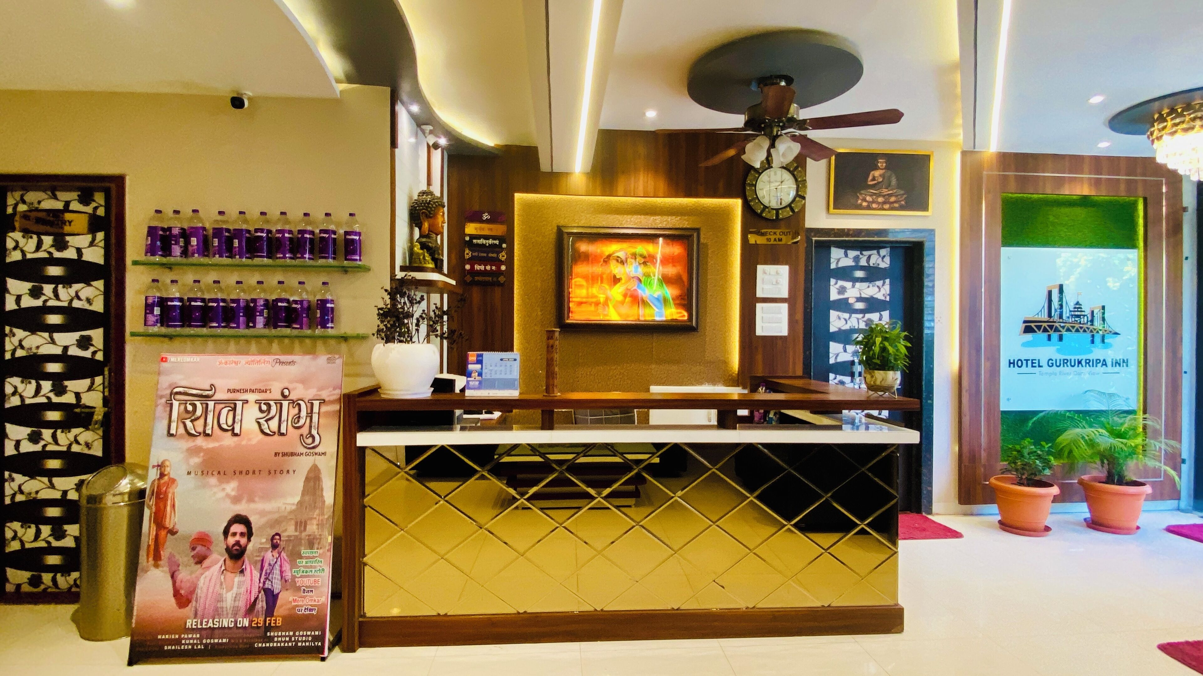 A hotel reception desk with a clock, a poster, and a green wall with a view of a bridge.