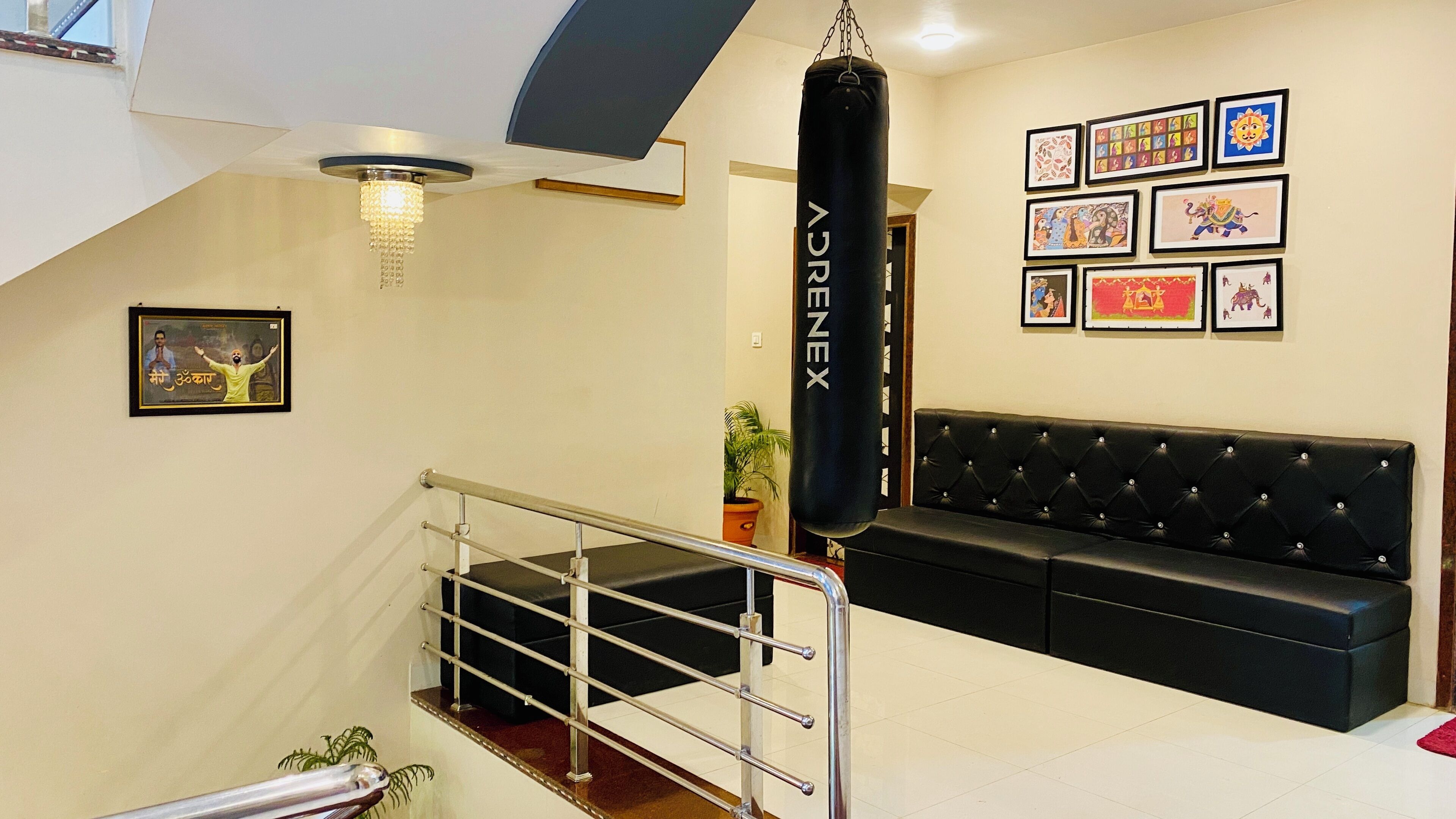 A hotel lobby with a black leather sofa, a punching bag labeled 'AENEX', a chandelier, and framed artwork on the walls.