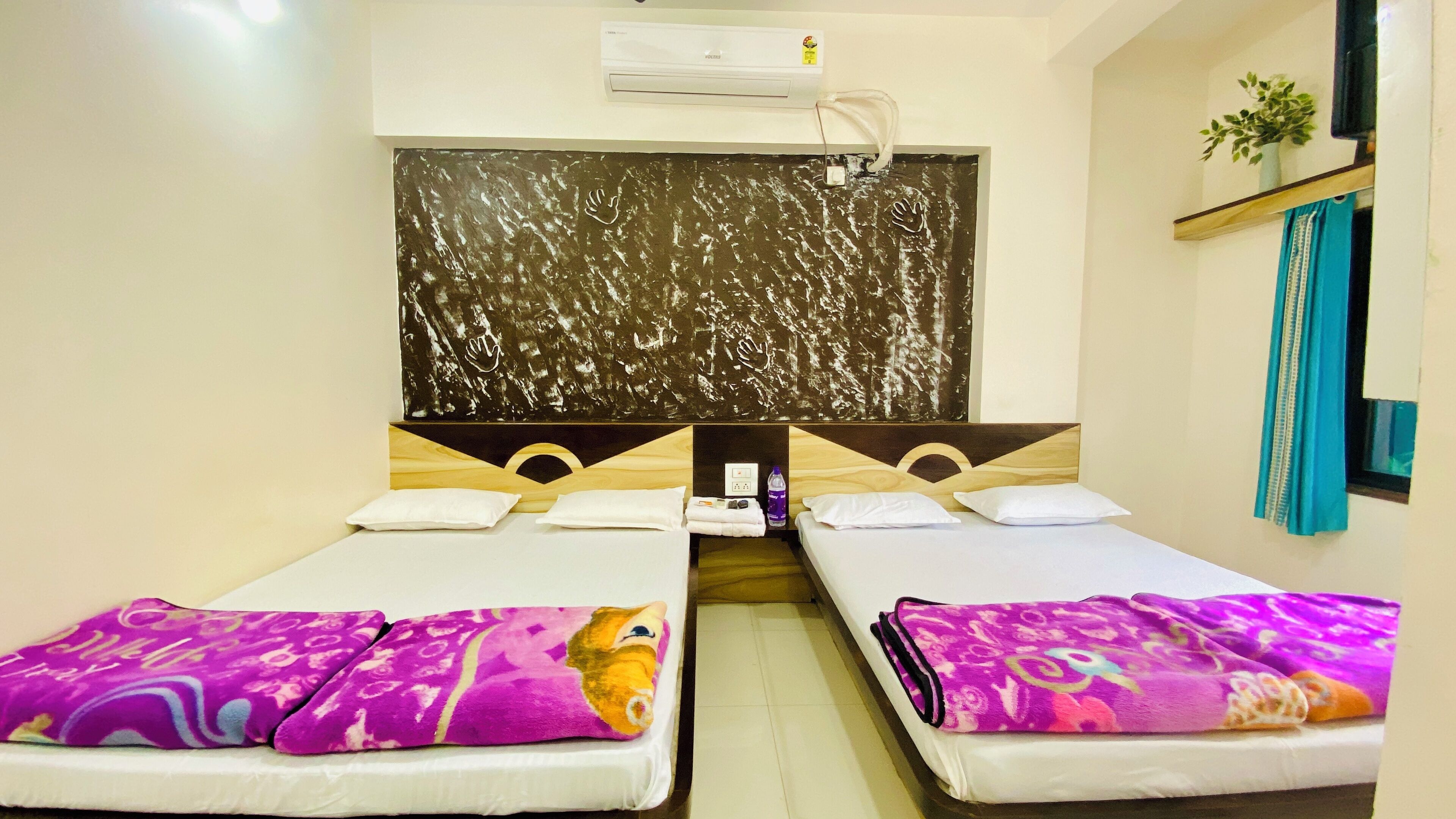 Une chambre d’hôtel avec deux lits simples, un grand miroir, un appareil de climatisation et une petite fenêtre avec un rideau.