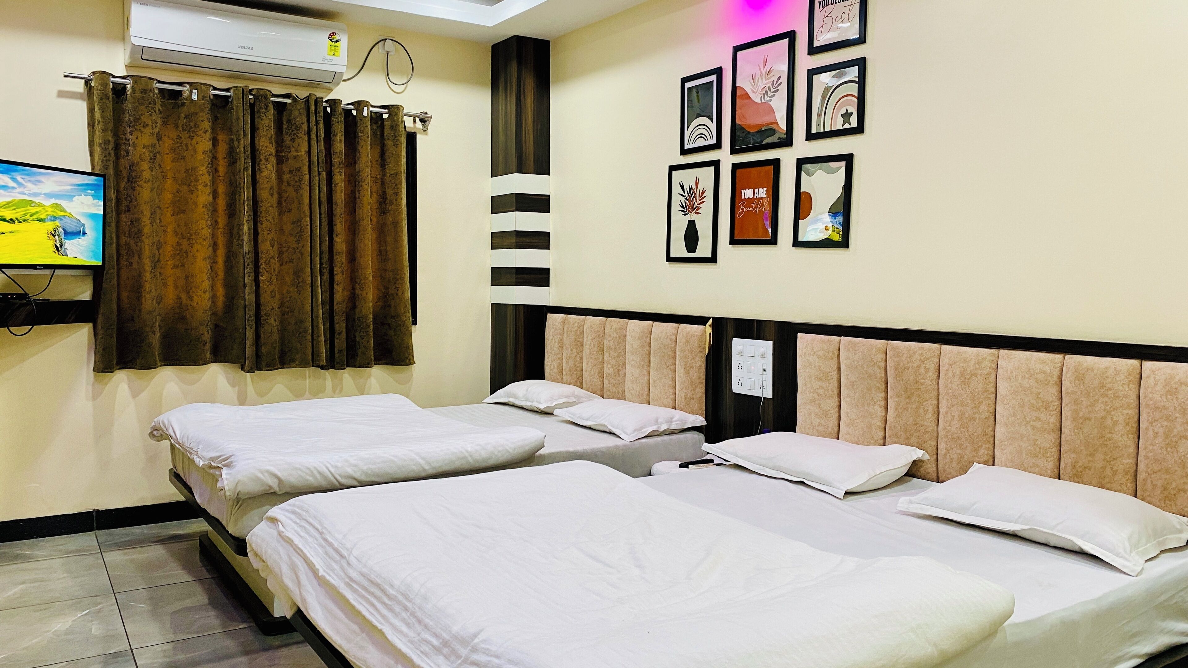 A hotel room with two beds, a TV, air conditioning, and motivational wall art.