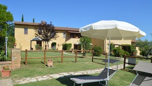 Un patio con mesa de billar, sillas de descanso y una sombrilla.