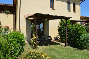 A building with a covered patio, a door, and a window. - Large Apartment With Shared Swimming Pool in Crete Senesi (Asciano)