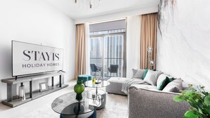 Un soggiorno moderno con un divano, un tavolino in vetro e una TV che mostra 'STAYIS HOLIDAY HOMES'.