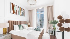 Camera d'hotel moderna con un letto grande, un comodino, un tavolino in vetro e vista sulla città.