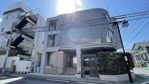 Um edifício moderno de dois andares com fachada curva, escadaria visível e entrada com portão.