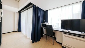 Quarto de hotel moderno com escrivaninha, cadeira e televisão de tela plana.