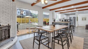 Cozinha espaçosa com eletrodomésticos modernos, área de jantar com mesa e cadeiras de madeira, e uma grande janela com vista para o quintal.