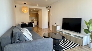 A modern living room with a grey sofa, a flat-screen TV, a small round table, and a potted plant. - RIBALTA B.1.1 (L'Escala)
