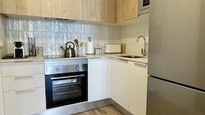A compact kitchen with a built-in oven, a microwave, and a stainless steel refrigerator.