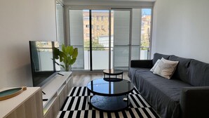 Un salon moderne avec un canapé, une table ronde, une plante et de grandes fenêtres.