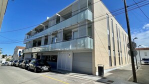 Un immeuble à plusieurs étages avec un garage, des voitures garées et un ciel dégagé.