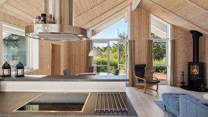 A modern kitchen with a built-in stove, a dining area with a view, and a cozy seating area with a fireplace.