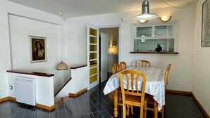 En matplats med ett bord och stolar, en trappa, ett kylskåp och ett fönster med utsikt över köket.