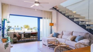 A modern living room with a sofa, coffee table, and a dining area with a view of the sea. - Beach Homes Punta Cana (Punta Cana)